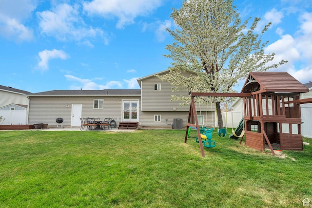 rear view of house with a lawn, fence private yard, central AC, a playground, and a patio