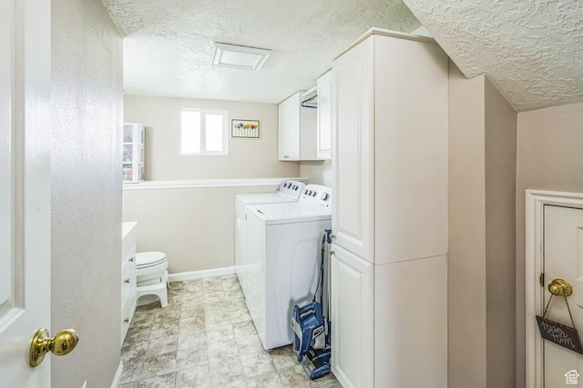 washroom with cabinet space, a textured ceiling, washing machine and dryer, and baseboards