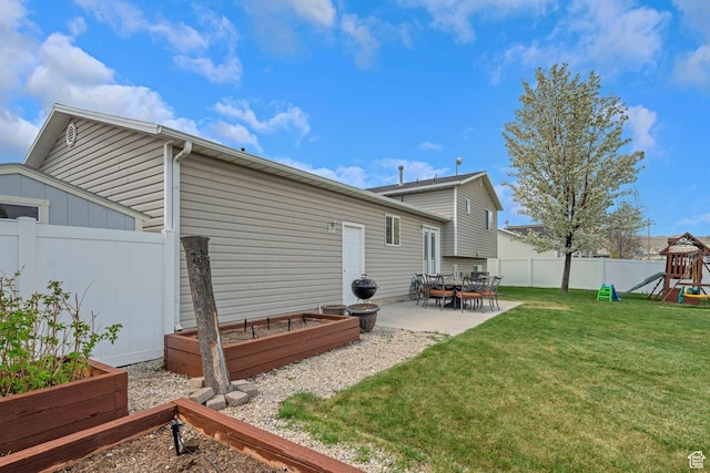 rear view of property featuring a garden, a patio area, a fenced backyard, a playground, and a yard