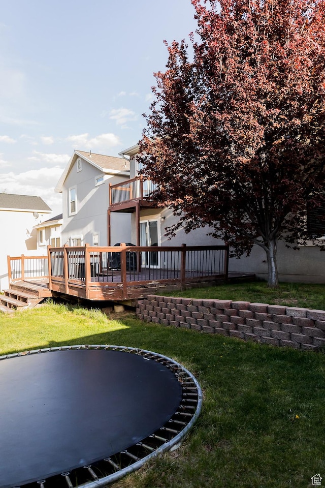 4866 W Spirit Lake Cir, Riverton, UT 84096 - rear view of house with fence, a trampoline, a wooden deck, a balcony, and a lawn