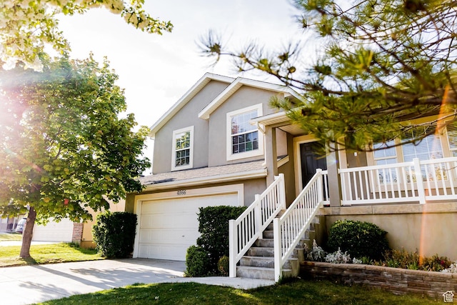 split level home with a garage, stucco siding, and driveway