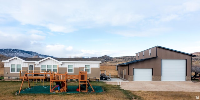 610 S Trout Dr, Manila, UT 84046 - view of front of property featuring an outdoor structure, a front lawn, a deck with mountain view, a playground, and a detached garage