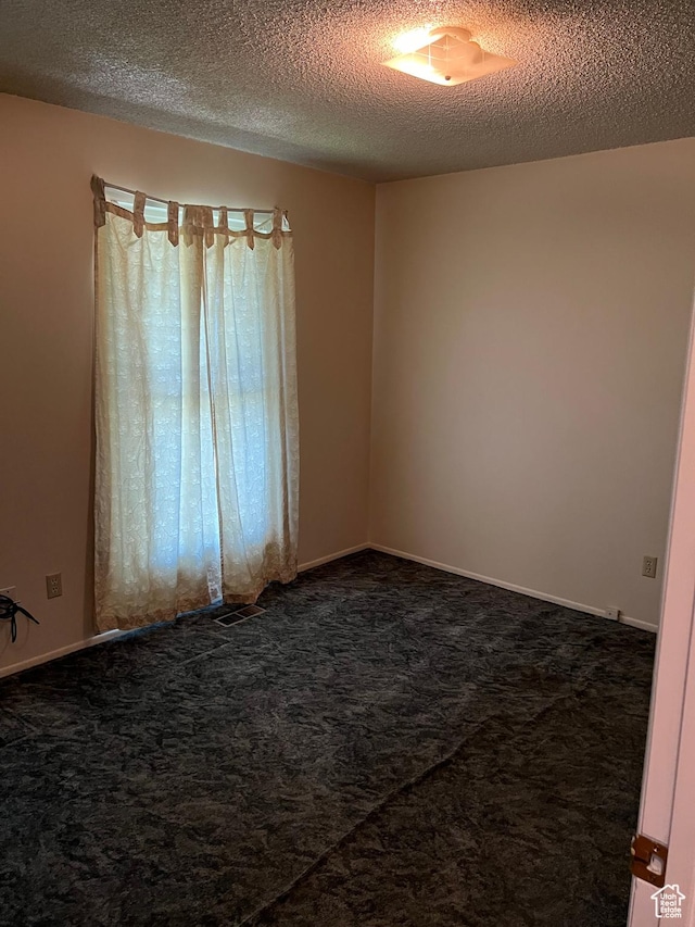 carpeted spare room with a textured ceiling