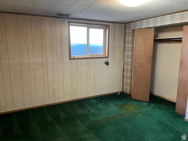 unfurnished bedroom with carpet flooring, wood walls, and a closet