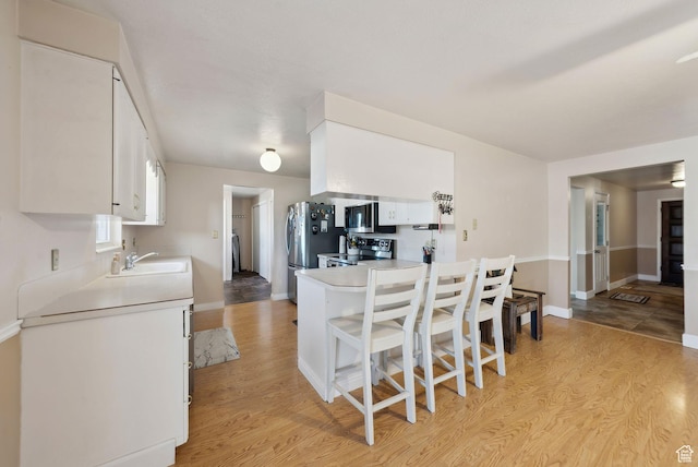 518 E Wendy Way S, Tremonton, UT 84337 - kitchen featuring baseboards, light wood-type flooring, white cabinets, a sink, and appliances with stainless steel finishes