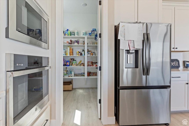 304 E Empire Springs Dr, Saratoga Springs, UT 84045 - kitchen featuring appliances with stainless steel finishes, light wood-style floors, and white cabinetry
