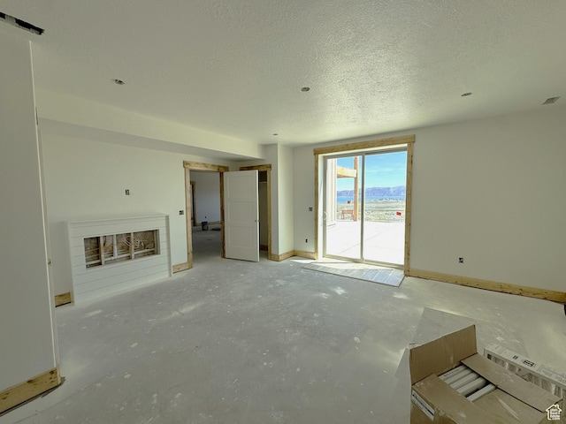 3042 S Chukar Dr, Garden City, UT 84028 - unfurnished living room with a fireplace, concrete floors, and a textured ceiling