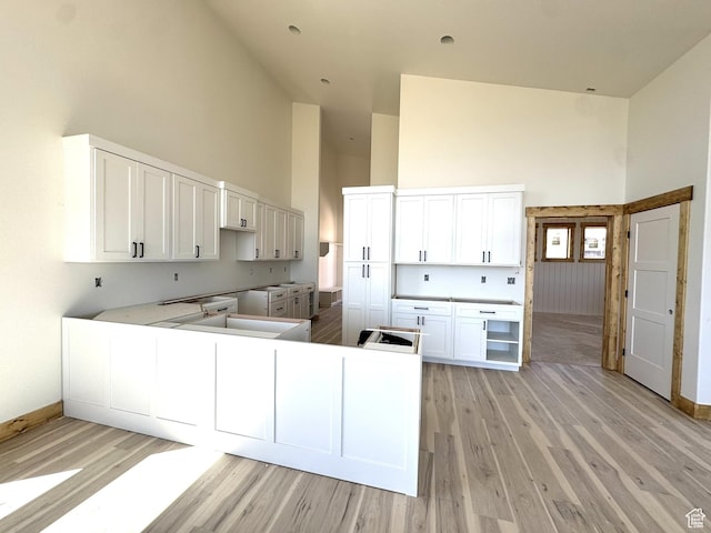 3042 S Chukar Dr, Garden City, UT 84028 - kitchen with high vaulted ceiling, baseboards, light wood-style flooring, and white cabinetry