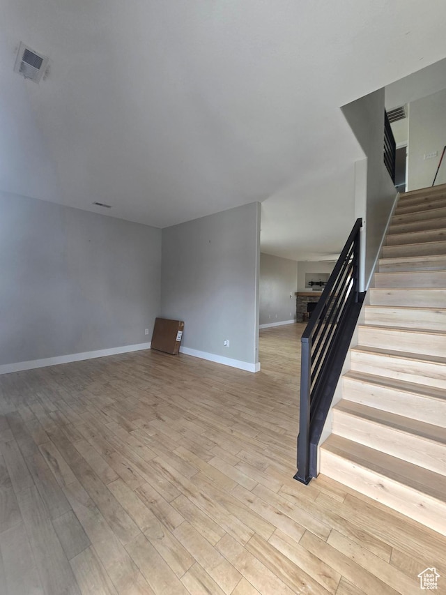 interior space with light wood-type flooring, visible vents, stairway, a fireplace, and baseboards