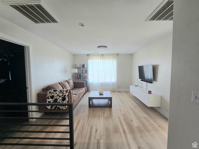 living area with baseboards, light wood-type flooring, and visible vents