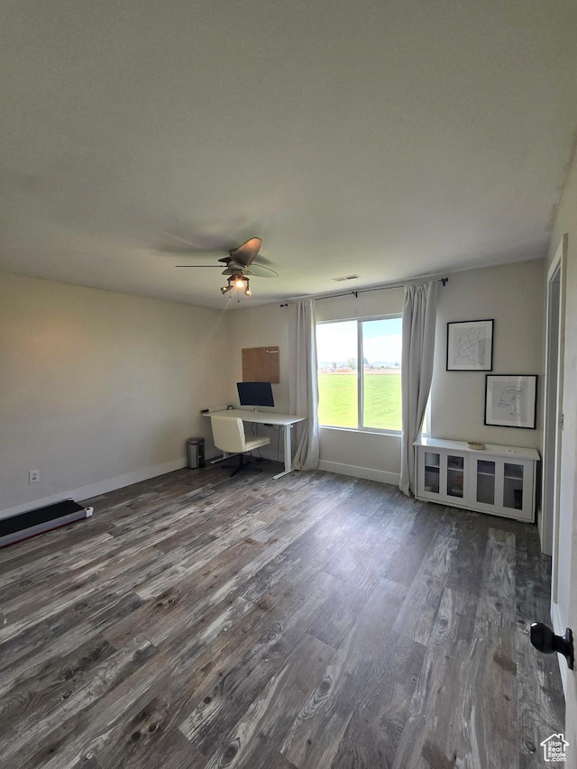 unfurnished living room featuring baseboards, a ceiling fan, and dark wood finished floors