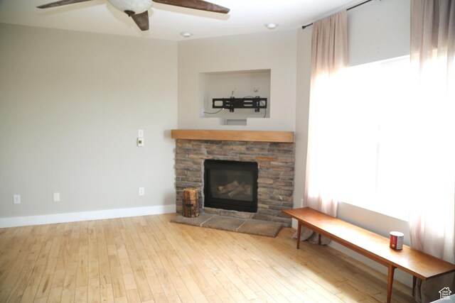 3596 W 2610 S, Syracuse, UT 84075 - living room featuring a stone fireplace, wood finished floors, a ceiling fan, and baseboards