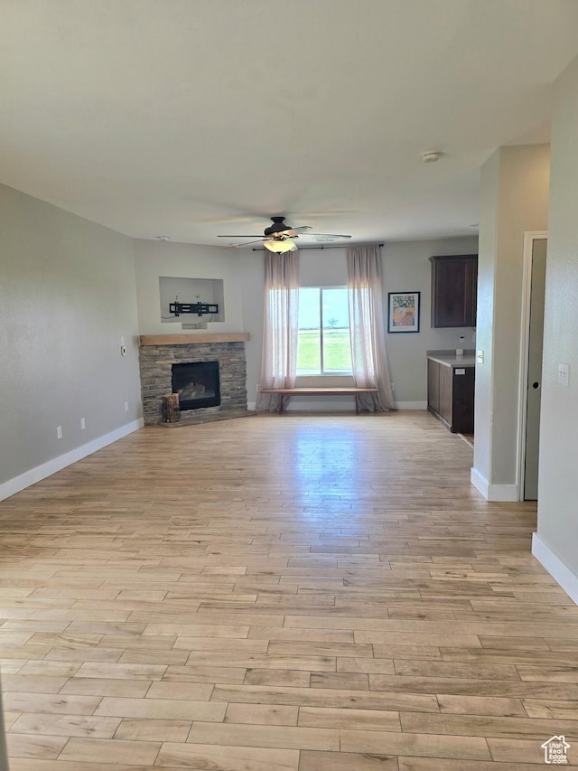 3596 W 2610 S, Syracuse, UT 84075 - unfurnished living room featuring light wood-style flooring, ceiling fan, baseboards, and a fireplace