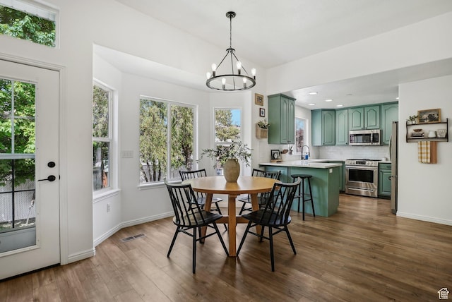 dining room with a chandelier, healthy amount of natural light, dark wood-type flooring, and recessed lighting