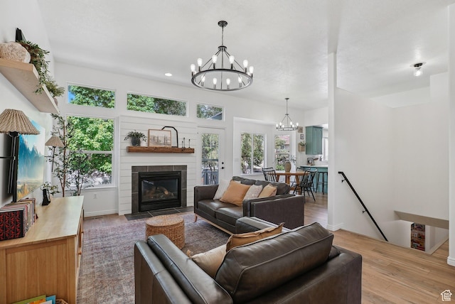 living area featuring a chandelier, wood finished floors, a fireplace with flush hearth, and recessed lighting
