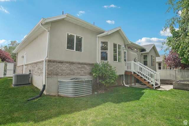 back of house with cooling unit, stucco siding, and brick siding