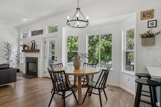dining area featuring wood finished floors, plenty of natural light, a chandelier, a fireplace, and recessed lighting