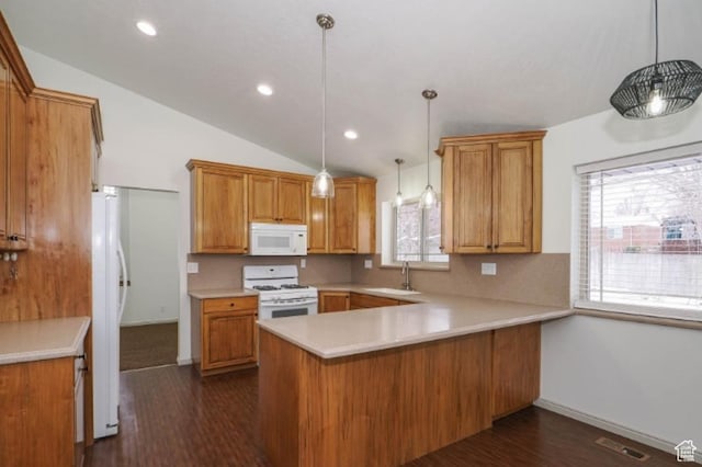 kitchen featuring a sink, light countertops, a peninsula, white appliances, and dark wood-type flooring