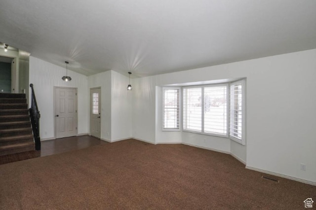 unfurnished living room featuring visible vents, baseboards, stairway, carpet flooring, and vaulted ceiling