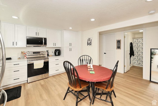 dining room featuring recessed lighting, a textured ceiling, baseboards, and light wood finished floors