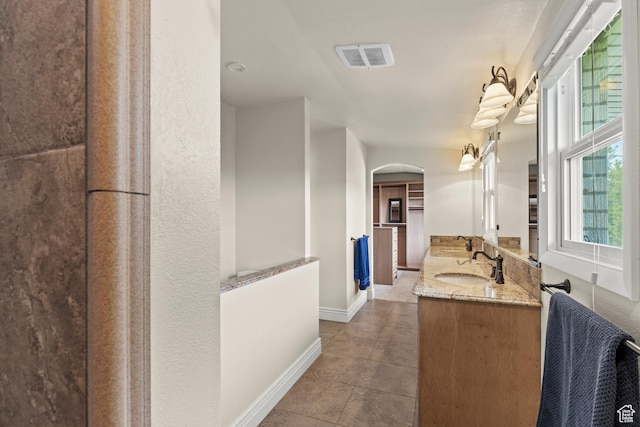 bathroom featuring visible vents, a sink, baseboards, and double vanity