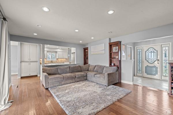 living room with baseboards, recessed lighting, and light wood-style flooring
