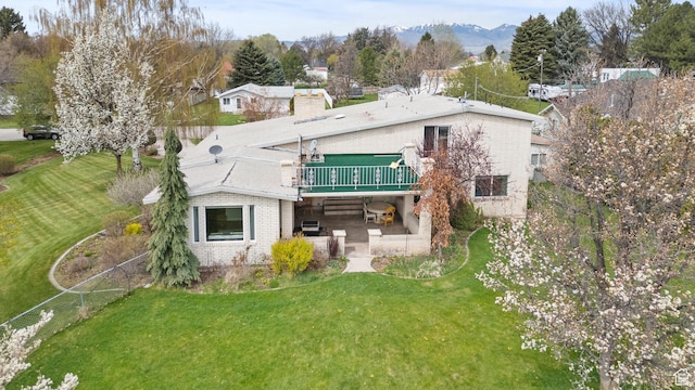 rear view of property featuring brick siding, a lawn, a wooden deck, and a patio area