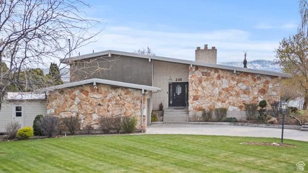 view of front of property with a chimney, a front lawn, and stone siding