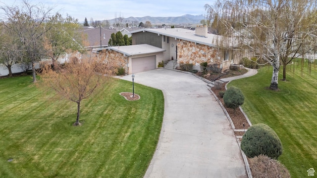 view of front of property featuring an attached garage, a chimney, a front yard, and concrete driveway