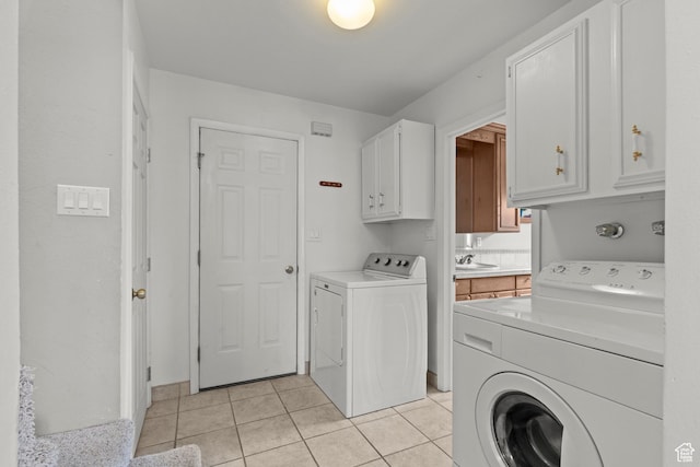 washroom with separate washer and dryer, a sink, cabinet space, and light tile patterned floors