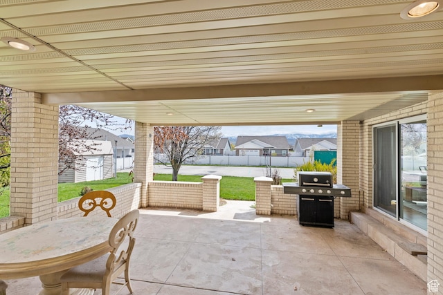 view of patio featuring fence, outdoor dining space, an outbuilding, and area for grilling
