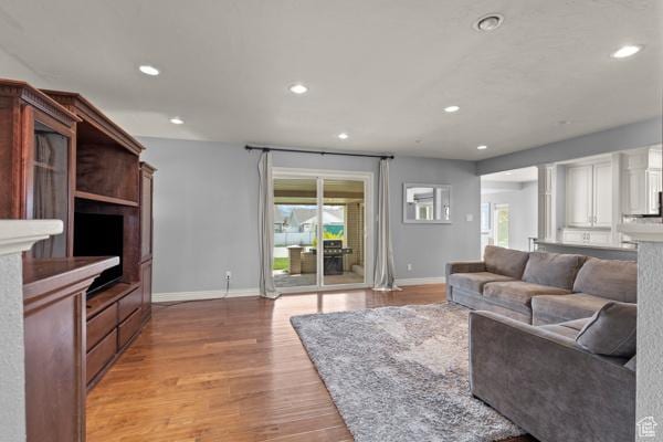 living room featuring light wood-style floors, baseboards, recessed lighting, and a wealth of natural light