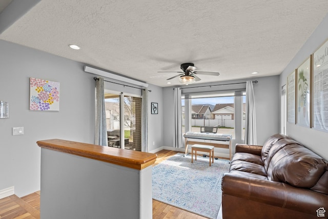 living area with light wood-style floors, ceiling fan, recessed lighting, and a textured ceiling