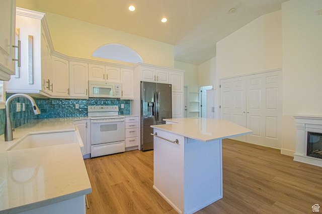 25 Clubhouse Dr, Stansbury Park, UT 84074 - kitchen featuring white appliances, white cabinets, tasteful backsplash, a sink, and light wood-style flooring