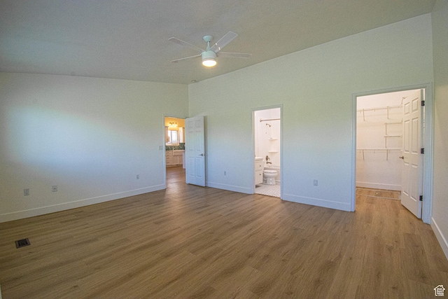 25 Clubhouse Dr, Stansbury Park, UT 84074 - unfurnished bedroom with a walk in closet, baseboards, wood finished floors, lofted ceiling, and visible vents