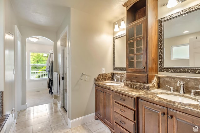 full bathroom featuring baseboards, a sink, tile patterned flooring, and double vanity