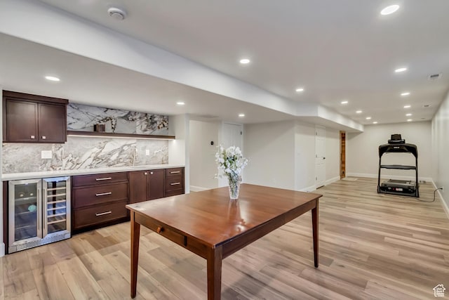 bar with beverage cooler, baseboards, decorative backsplash, light wood-type flooring, and a bar