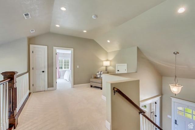 hallway with light carpet, baseboards, an upstairs landing, vaulted ceiling, and visible vents