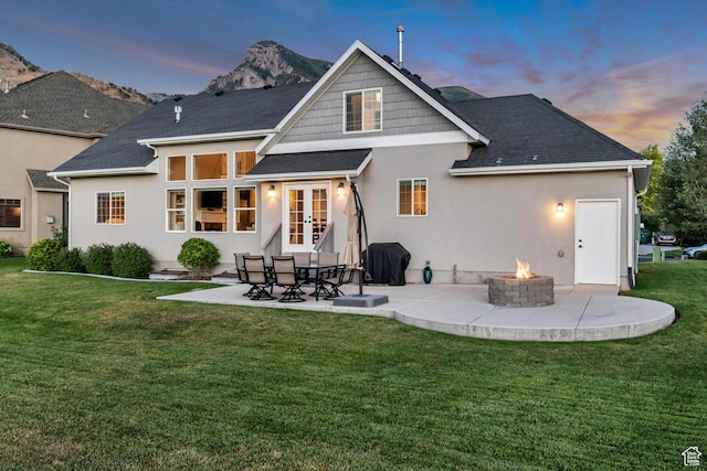 back of house at dusk featuring stucco siding, french doors, a patio area, and an outdoor fire pit