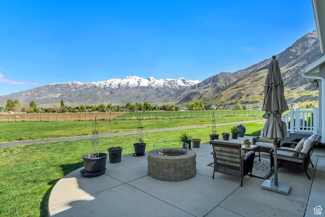 view of patio / terrace featuring an outdoor living space with a fire pit, a mountain view, a rural view, and fence