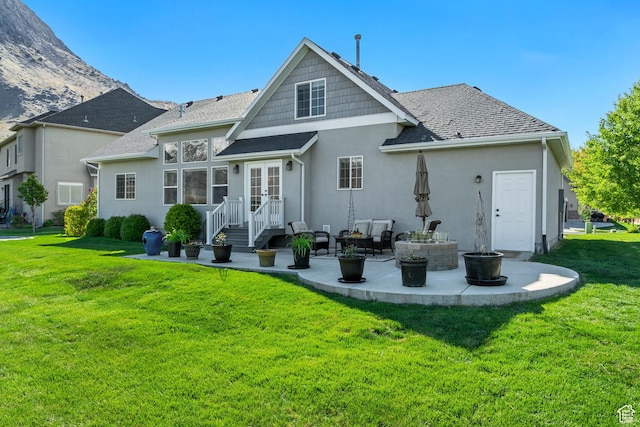 back of property with french doors, a lawn, a patio area, a shingled roof, and stucco siding