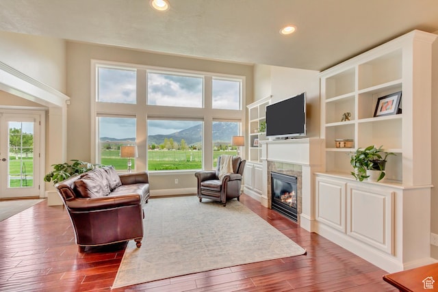 living room featuring baseboards, recessed lighting, dark wood-style floors, and a tile fireplace