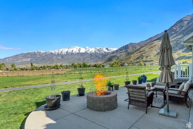 view of patio with fence, an outdoor living space with a fire pit, a mountain view, and a rural view