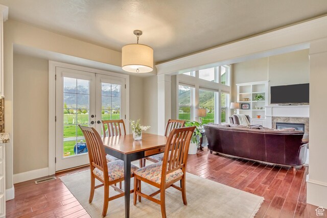 dining space with french doors, visible vents, a healthy amount of sunlight, and wood finished floors