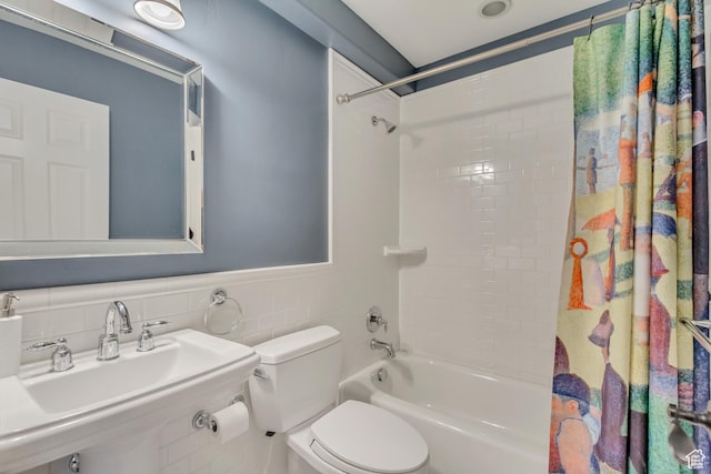 full bathroom featuring a sink, shower / tub combo with curtain, toilet, and tile walls