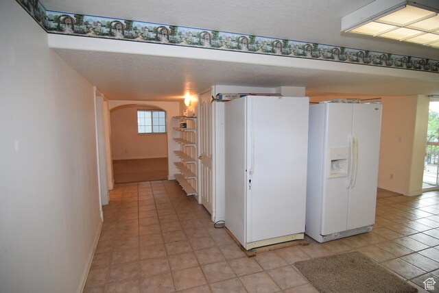 183 E Ama Fille Ln N, Elk Ridge, UT 84651 - kitchen featuring white fridge with ice dispenser, freestanding refrigerator, arched walkways, baseboards, and light tile patterned floors