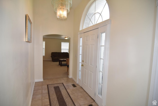 183 E Ama Fille Ln N, Elk Ridge, UT 84651 - foyer entrance with arched walkways, light tile patterned flooring, a high ceiling, baseboards, and light colored carpet
