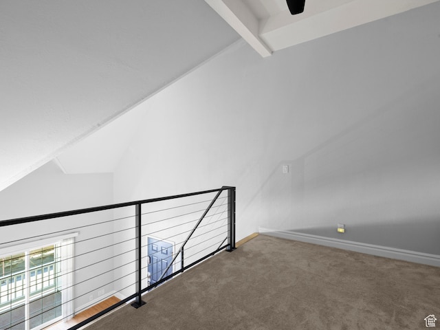 interior space featuring carpet flooring, baseboards, a ceiling fan, and vaulted ceiling with beams