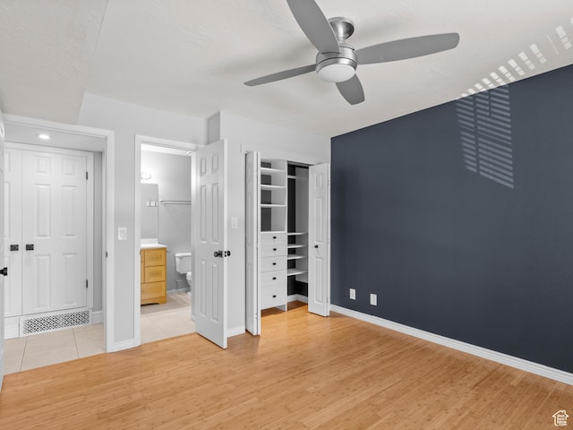 unfurnished bedroom featuring baseboards, ensuite bathroom, light wood finished floors, and visible vents