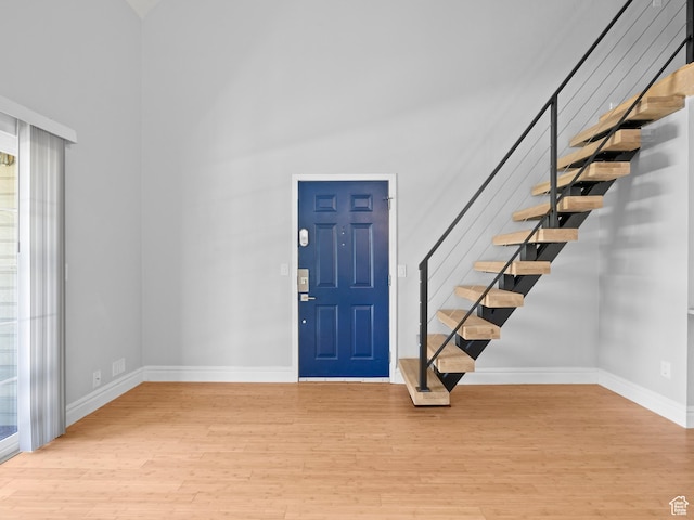 foyer entrance featuring baseboards, stairway, a high ceiling, and wood finished floors
